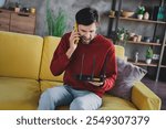 Young man in casual pullover frustrated with home internet issues, holding router and phone indoors on weekend day