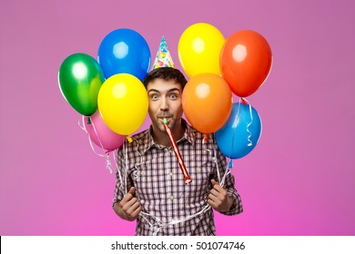 Young Man Celebrating Birthday, Holding Colorful Baloons Over Purple Background.