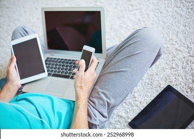 Young man with cellphone, touchpad and laptop