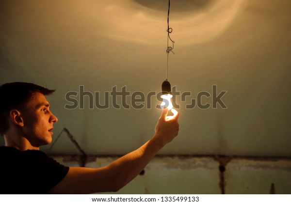 Young Man Changes Light Bulb On Stock Photo Edit Now 1335499133