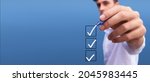 Young man checking boxes with list of 3 options on blue background