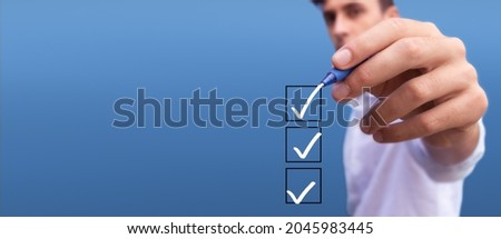 Young man checking boxes with list of 3 options on blue background