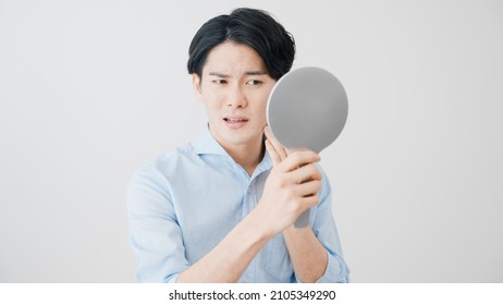 Young Man Checking His Skin With A Hand Mirror Skincare