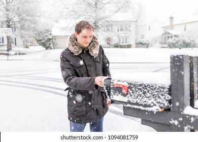 Young Man Checking Mail In Neighborhood Road With Snow Covered Ground During Blizzard White Storm, Snowflakes Falling In Virginia Suburbs, Single Family Homes In Mailbox Box