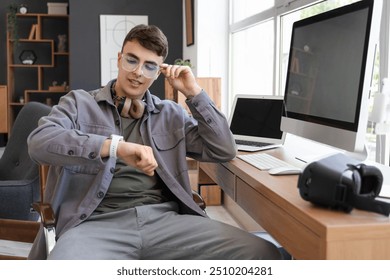 Young man checking smartwatch at desk in office - Powered by Shutterstock