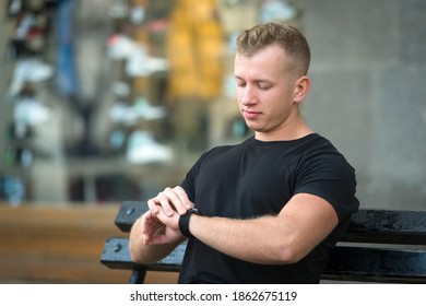 young man checking time while sitting on a bench