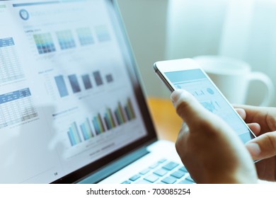 Young Man Checks Business Report By Laptop And Mobile Phone