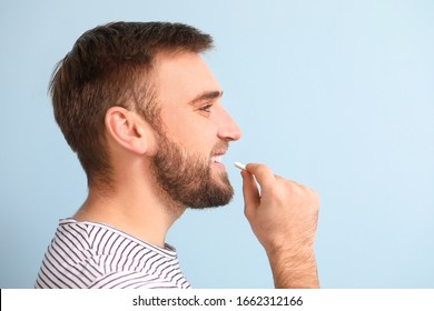 Young Man With Chewing Gum On Color Background