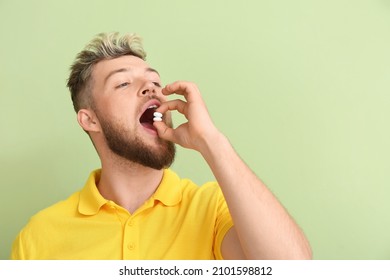 Young Man With Chewing Gum On Color Background