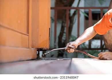young man chooses to use termite control chemicals that are not toxic to humans mixed with water in tank for spraying to eliminate termites. enabling young man to spray termite repellant by himself - Shutterstock ID 2311960047