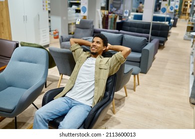 Young man choosing chair in furniture store