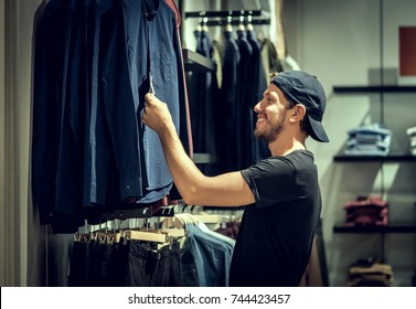 Young Man Choosing Clothes In Shopping Mall 