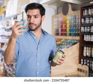 Young Man Choosing Materials For Home Renovation In Paint Store