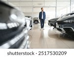 Young man is choosing a new vehicle in car dealership.