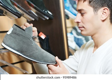 Young Man Choosing Shoes During Footwear Shopping At Shoe Shop