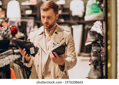 Young Man Choosing Sneakers At Sportswear Shop