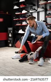 Young Man Choosing Sneakers At Sportswear Shop