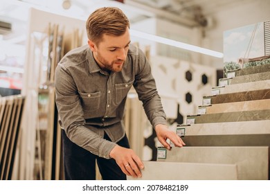 Young Man Choosing Tiles At Building Market