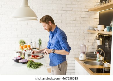 Young Man Chopping Vegetables In The Kitchen