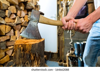 Young man chops firewood or wood with a hatchet or an axe in a shack in the mountains - Powered by Shutterstock