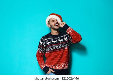 Young Man In Christmas Sweater And Hat On Color Background