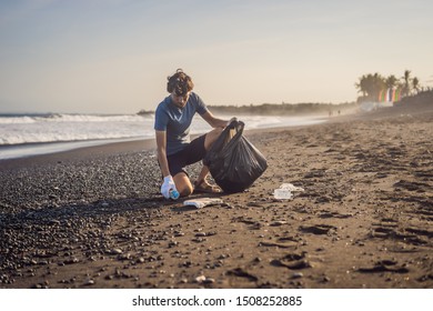 Young man cleaning up the beach. Natural education of children - Powered by Shutterstock