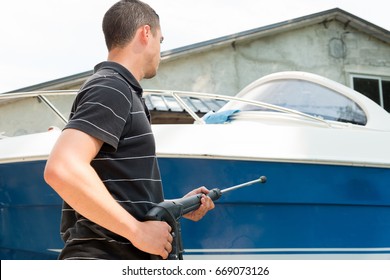 a young man cleaning boat with high pressure water