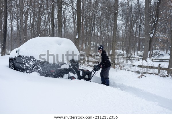 young man cleaning driveway with snow blower after\
the snow storm