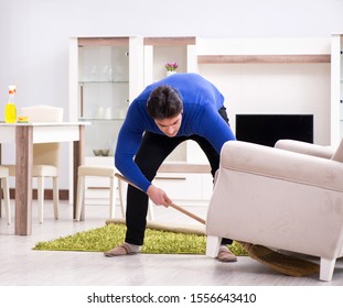 Young Man Cleaning Floor With Broom