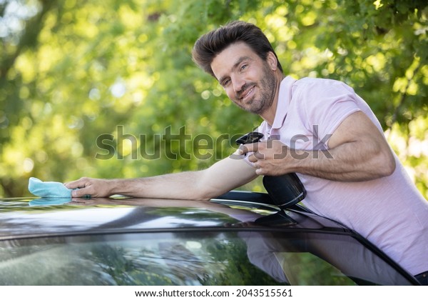 young man cleaning\
glass roof on his car
