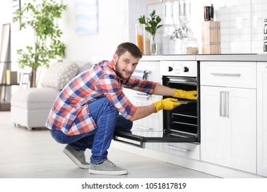 Young Man Cleaning Oven In Kitchen