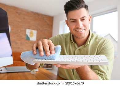 Young Man Cleaning PC Keyboard At Home