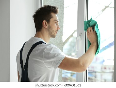 Young Man Cleaning Window In Office