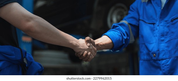 Young man client shaking hands with auto mechanic in red uniform having a deal at the car service - Shutterstock ID 2279962015