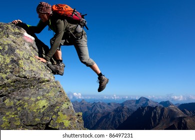 Young man climbing the mountain ridge