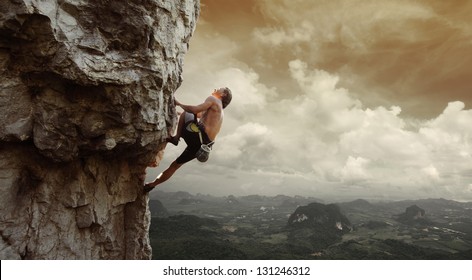 Young man climbing natural rocky wall with tropical valley on the background
