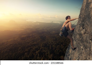 Young man climbing natural rocky wall at sunrise - Powered by Shutterstock