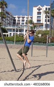 Young Man Climbing Rope On Beach