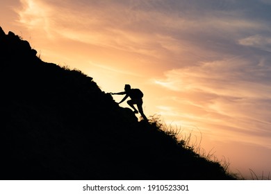 Young man climbing up to top of mountain. Self improvement and motivational goals concept. 