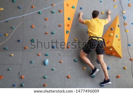 Young man climbing wall in gym