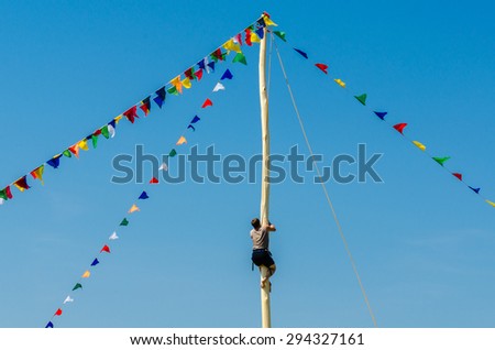 A young man climbs a pole for fun during the holiday Sabantuy