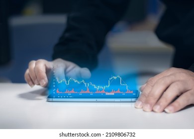 A Young Man In A Coat Is Scrolling Through The Digital Screen Of His Mobile Phone With His Hands. And Use Your Hand To Scroll The Screen And See The Stock Chart That Is Being Displayed.