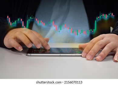 A Young Man In A Coat Is Scrolling Through The Digital Screen Of His Mobile Phone With His Hands. And Use Your Hand To Scroll The Screen And See The Stock Chart That Is Being Displayed.