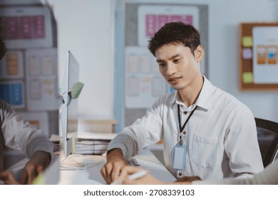 Young man collaborating with colleague, developing UIUX design and mobile application concepts in a modern office setup