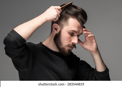 Young Man Comb His Hair On Gray Background