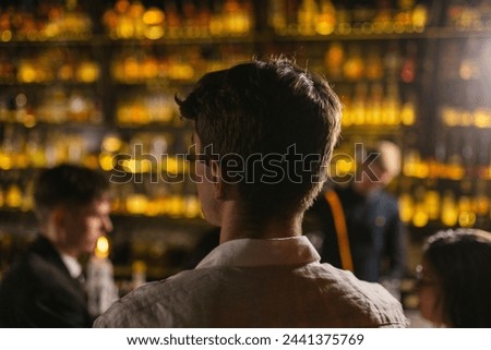 Young man comes to dance in modern night club with bright lamps. Guests have fun together at cocktail party with music in fancy place