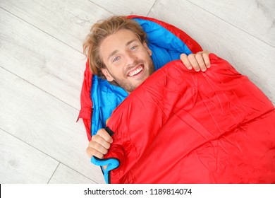 Young Man In Comfortable Sleeping Bag On Floor, Top View