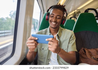Young Man Commuting To Work Sitting  On Train Streaming And Watching Film Or Show On Mobile Phone