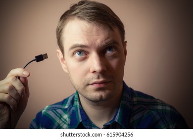 Young man with computer cable in his hand. Selective focus.