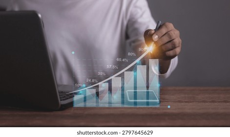 Young man with computer notebook and smartphone hand touching to visualize money growth The phone screen displays graphs and charts showing increasing investment and savings trends, increased account